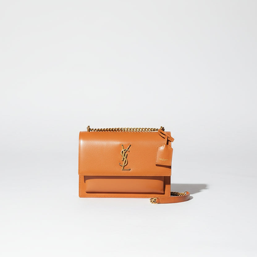 Yves Saint Laurent YSL Sunset Shoulder Bag Person holding a brown handbag with a plain background