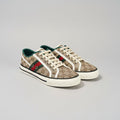 Pair of Gucci sneakers on a dark surface with a patterned box in the background.