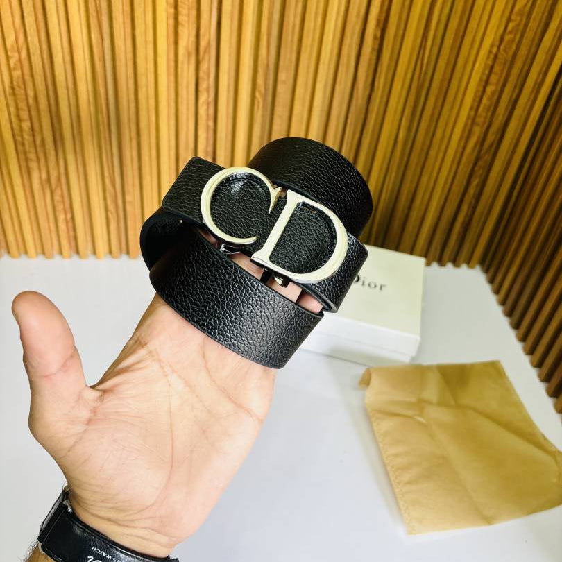 Black leather belt with gold buckle held by a hand against a wooden background