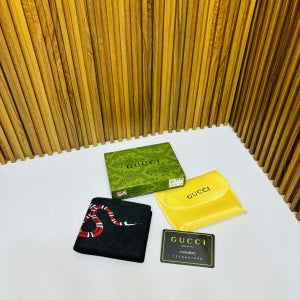 Gucci branded items including a wallet, card holder, and soap on a white surface with a wooden background.
