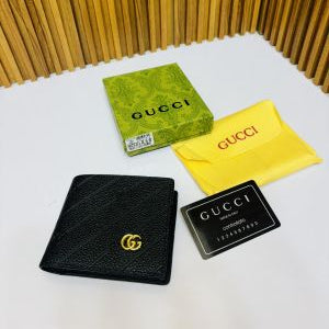 Black Gucci men wallet with green box, yellow cloth, and black card on a white surface.