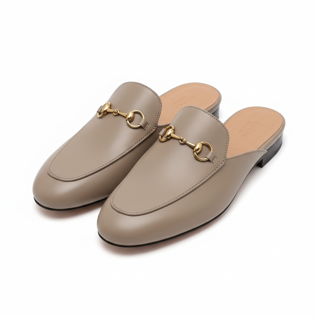 Brown Gucci mules slip-on shoes with gold accents on a light gray background