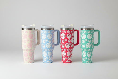 40 oz Stainless Steel Insulated Tumbler with Handle and Smiley Face Design – Durable Travel Mug with Straw Lid Four tumblers with smiley face patterns on a wooden surface