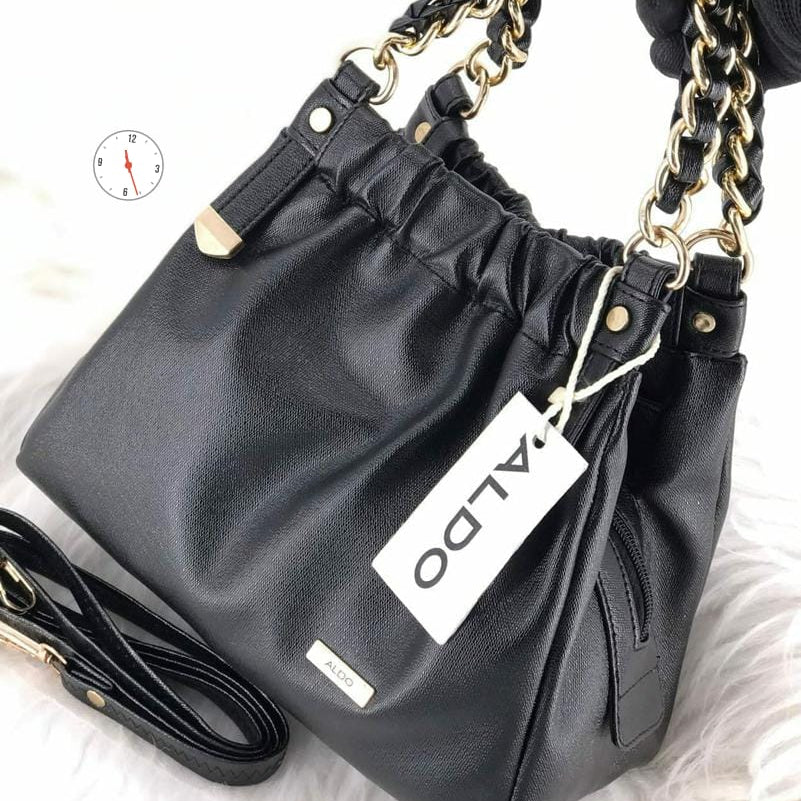 Black handbag with gold chain strap and Aldo label on a white background