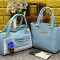 Two light blue handbags with 'Ted Baker London' branding on a textured surface.