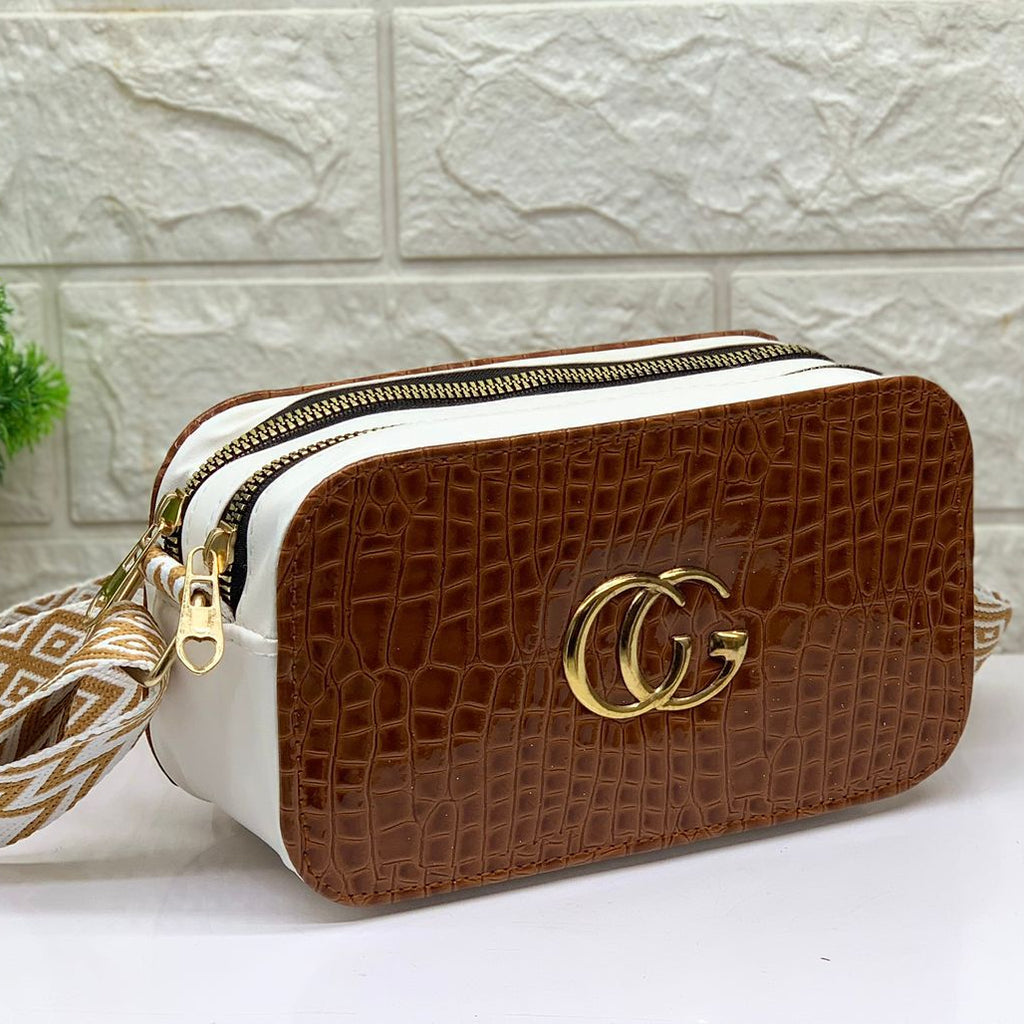 Brown and white handbag with gold accents on a light background