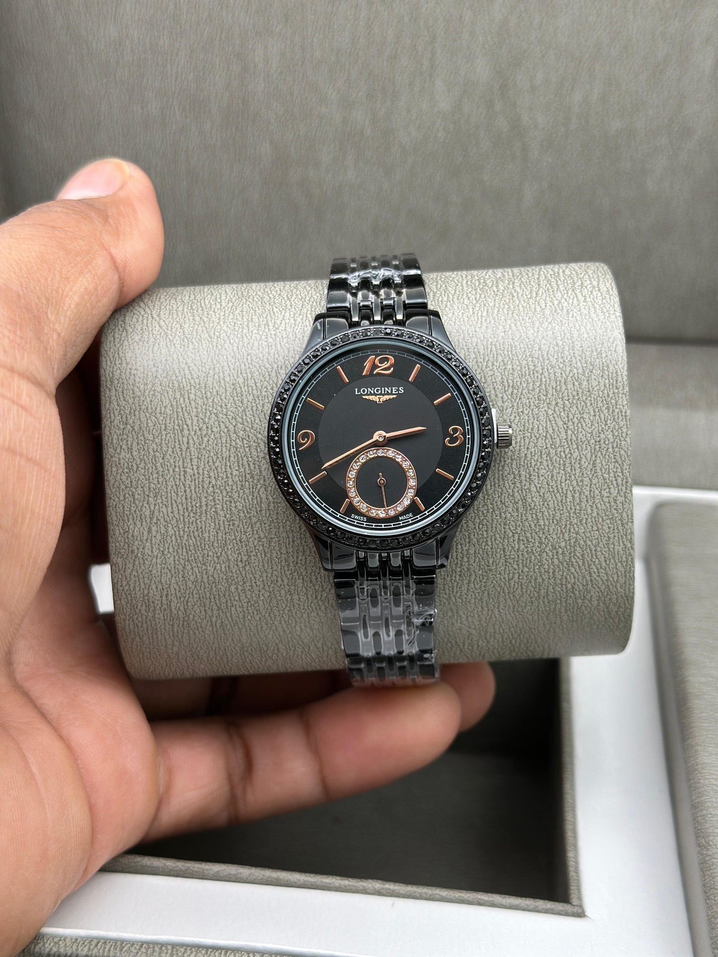 Longines watch held by a hand on a gray cushion