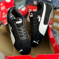 Black and white Puma sneakers in a red shoe box with blurred background
