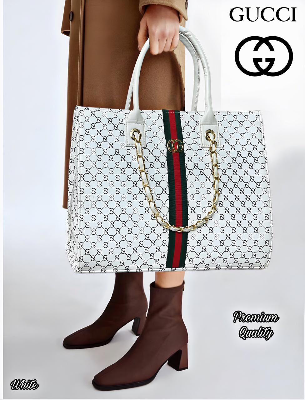 Gucci handbag with monogram pattern and red and blue stripe held by a person wearing brown shoes.