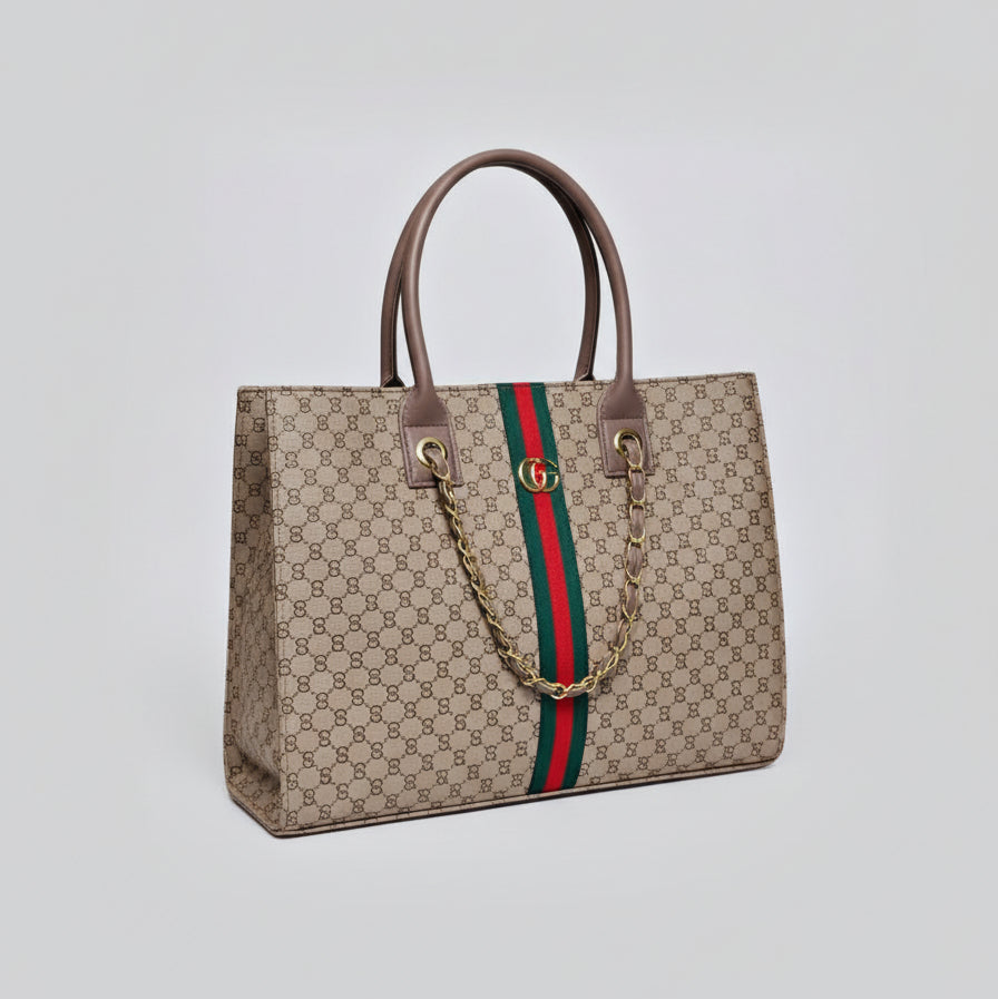 Beige Gucci handbag with monogram pattern and red and green stripes held by a person wearing brown boots.