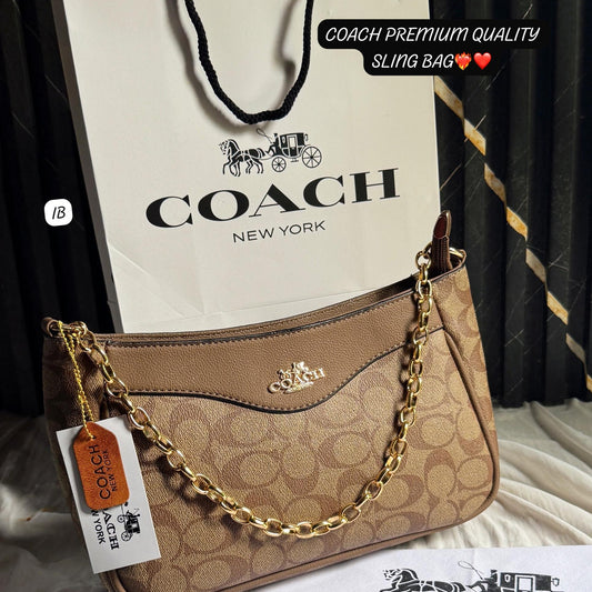 Coach handbag with gold chain and Coach branded paper bag on a dark background