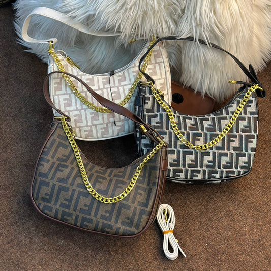 Two handbags with gold chains on a brown surface with a white fluffy blanket in the background.