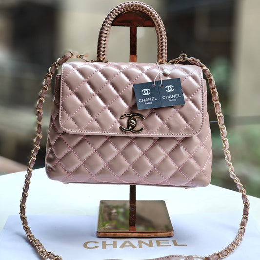 Pink quilted Chanel handbag with gold chain on a stand