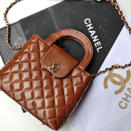 Brown quilted handbag with Chanel logo on a Chanel box and paper