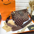 Designer handbag with checkered pattern on an orange Louis Vuitton packaging box.