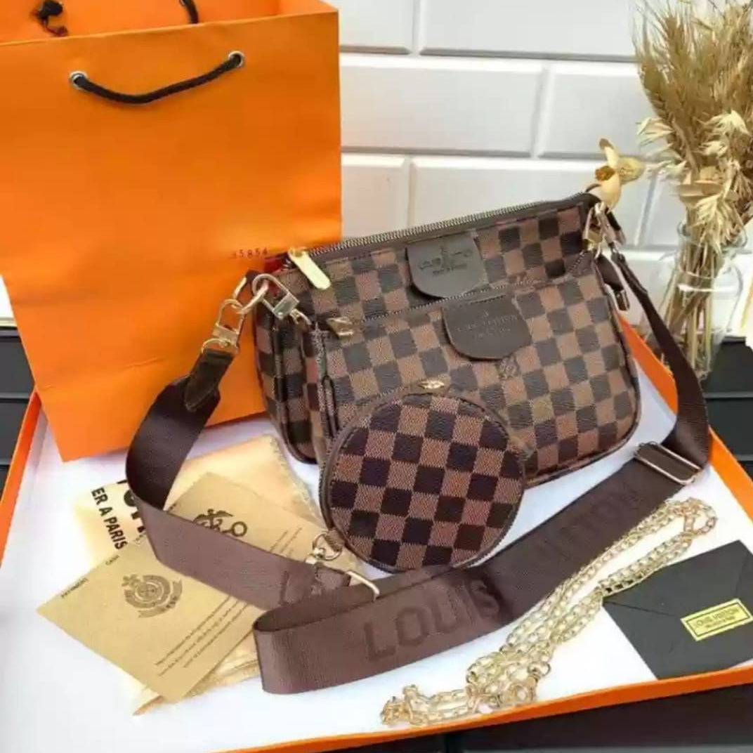 Designer handbag with checkered pattern on an orange Louis Vuitton packaging box.