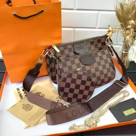 Designer handbag with checkered pattern on an orange Louis Vuitton packaging box.