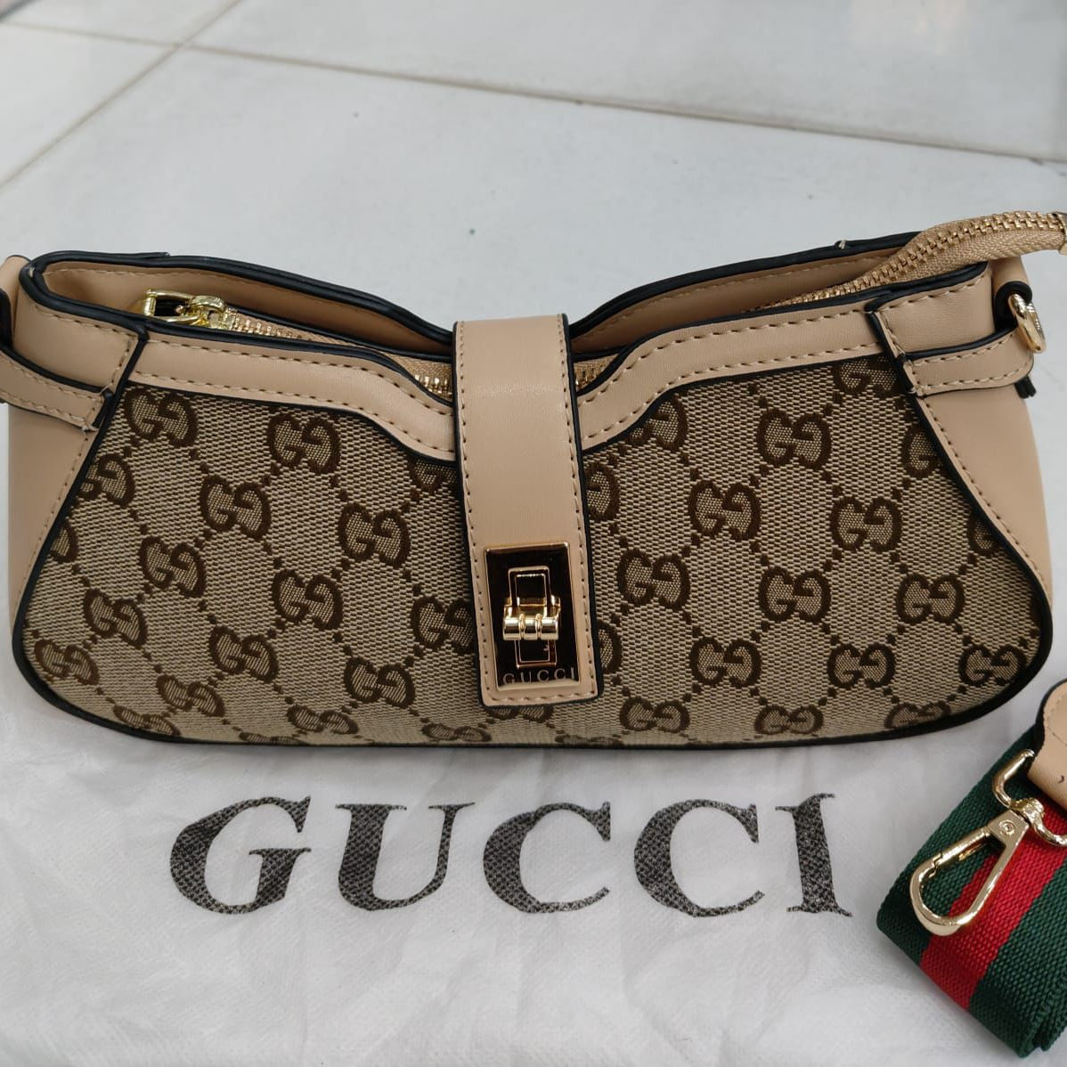 Beige Gucci handbag with monogram pattern on a white surface