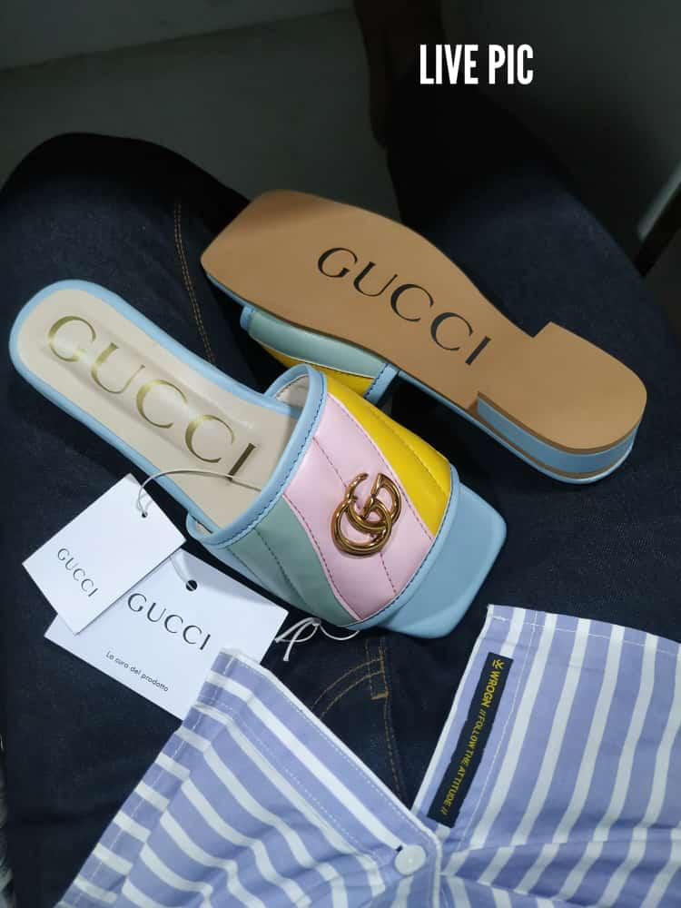 Gucci slide sandal with pink interior and gold logo, displayed with Gucci packaging.
