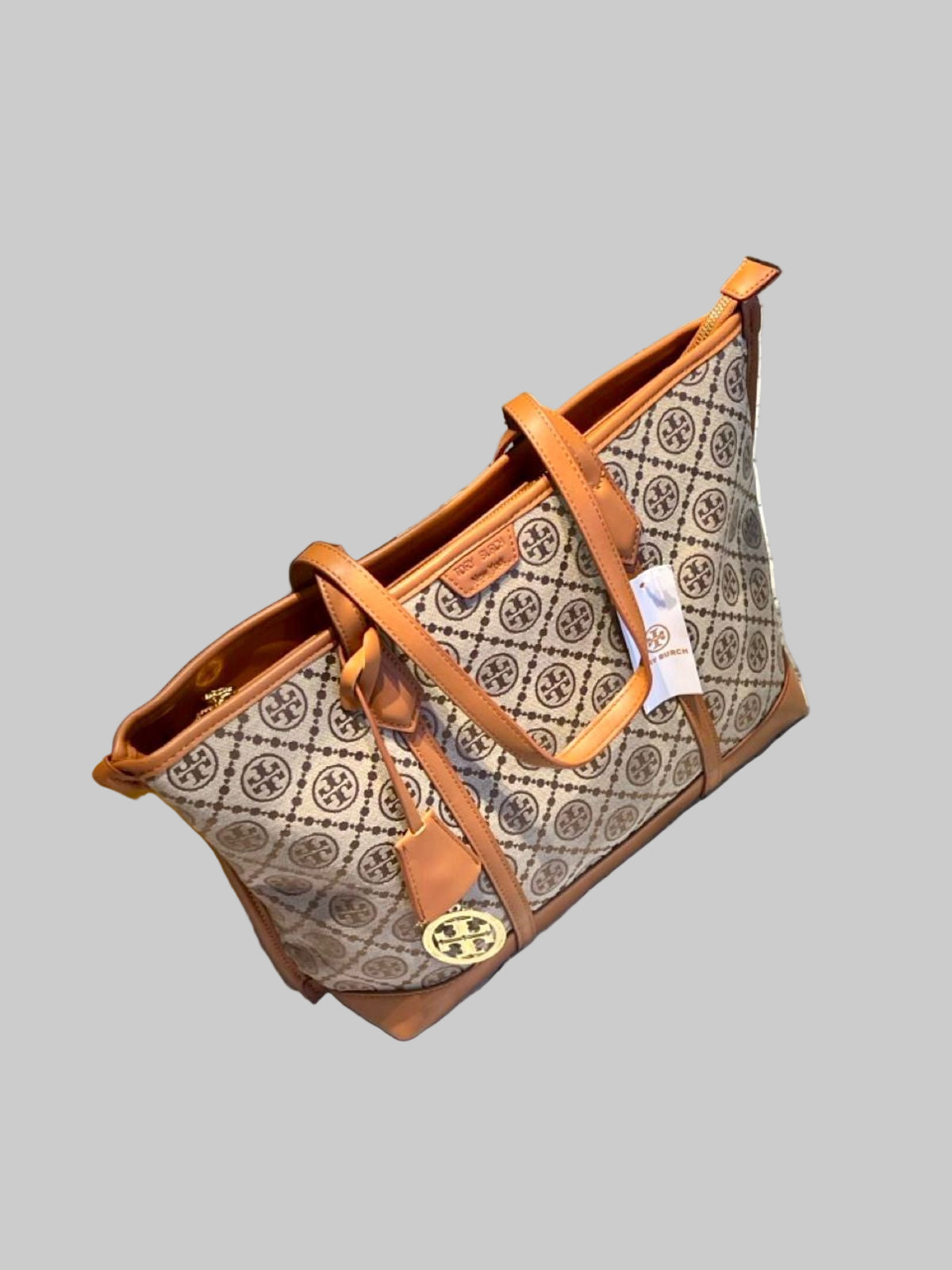Patterned handbag with brown leather straps on a concrete surface