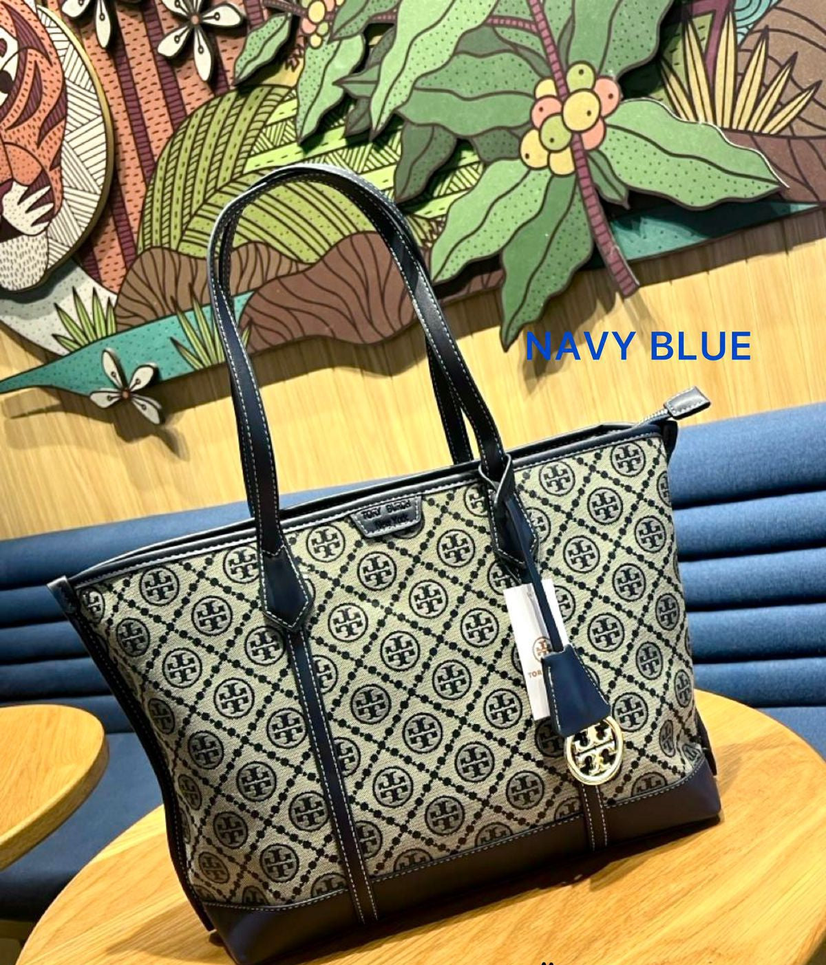 Navy blue handbag with a pattern on a wooden surface with colorful background
