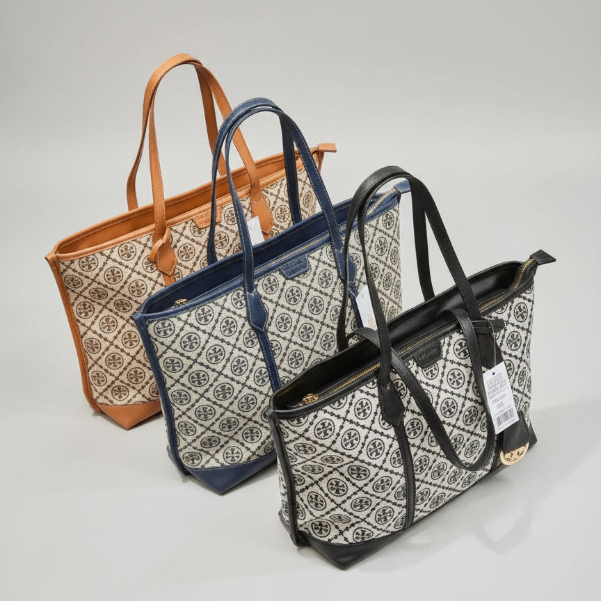 Three bags in tan, navy blue, and black with a pattern on a marble surface.