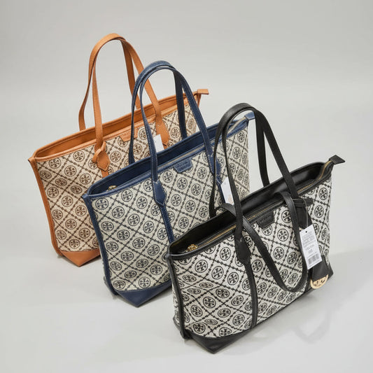 Three bags in tan, navy blue, and black with a pattern on a marble surface.