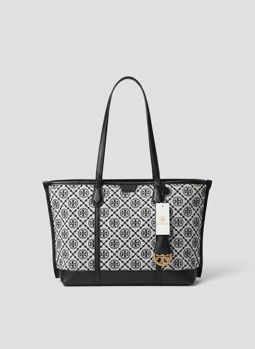 Black and white patterned handbag with a visible brand tag on a surface with greenery in the background.