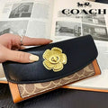 Coach wallet with floral emblem held over an open magazine featuring Coach branding.