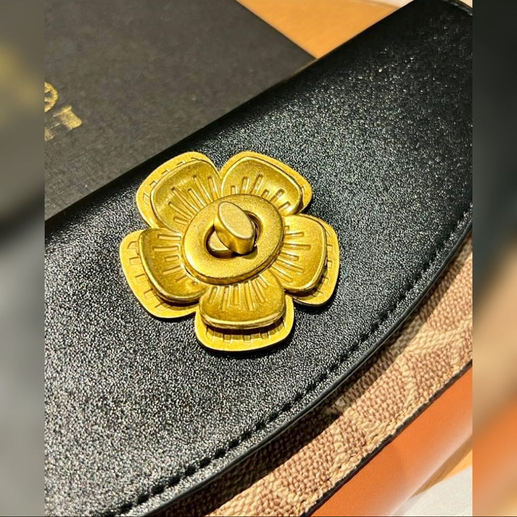 Coach handbag with a gold flower detail on a blurred background