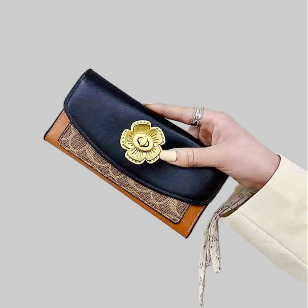 Hand holding a Coach wallet with gold emblem on a light gray background