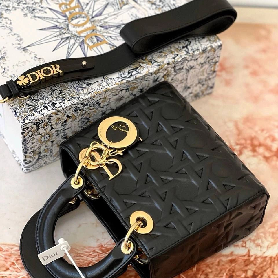 Black Dior handbag with gold accents on a textured surface