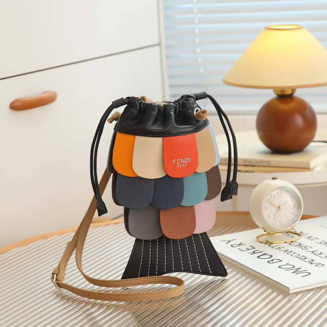 Black Fendi Fish Sling Bag  Colorful handbag with Fendi logo on a table with a lamp and books in the background