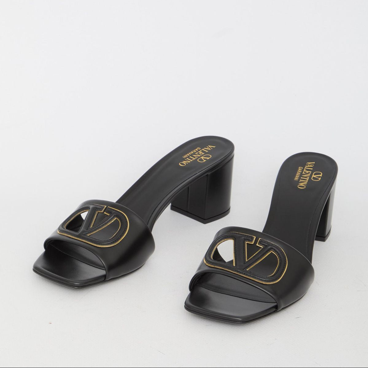 Black high-heeled sandals with a logo on a white background