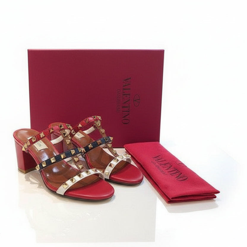 Red Valentino sandals with studded design on a white surface, accompanied by a red box and pouch.