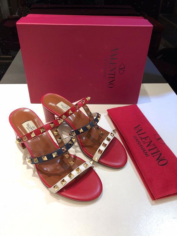 Red Valentino sandals with studded design on a white surface with a red box in the background.