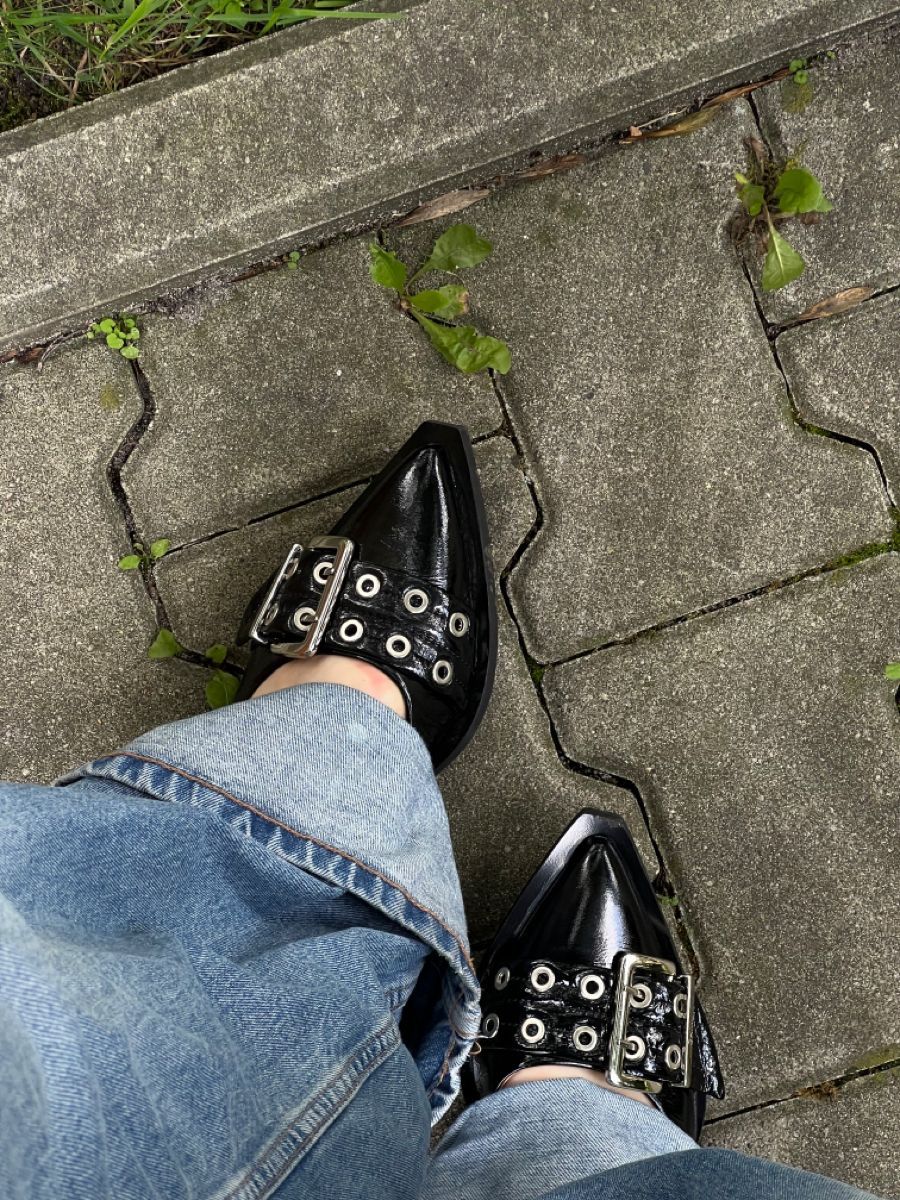 Black CHLOÉ Western Look Footwear  pointed-toe shoes with silver buckles worn on a concrete surface.