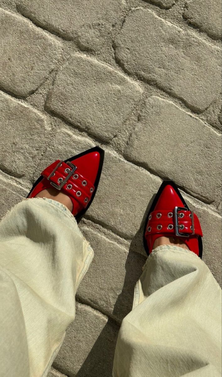 Red CHLOÉ Western Look Footwear  high-heeled shoes with studded details on a stone pavement against a brick wall.