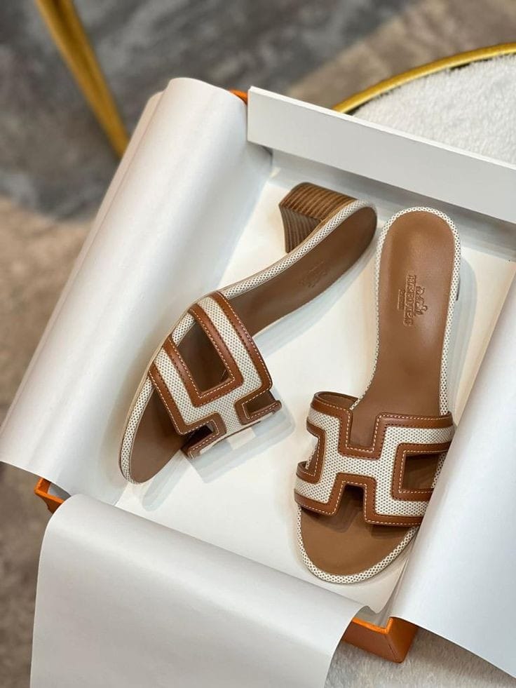 Brown HERMES Heel and beige sandals with a logo on a white surface