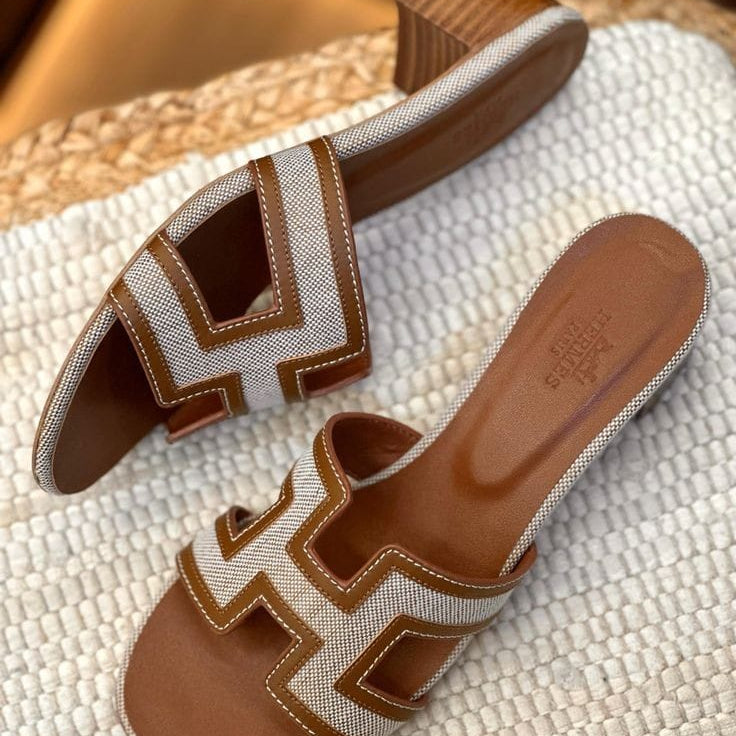 Brown HERMES Heel Pair of brown and beige sandals with a distinctive logo on a textured surface.