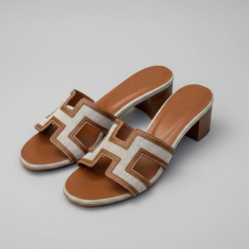 Brown HERMES Heel Pair of brown and beige sandals with a distinctive logo on a textured surface.