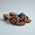 Navy blue HERMES Heel Pair of blue and brown sandals with Hermès logo on a white surface.
