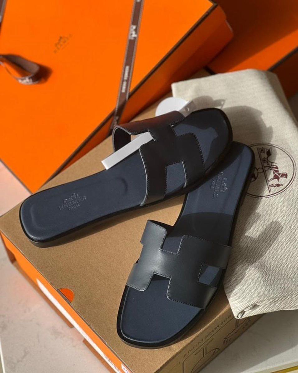 Grey HERMES Oran Velvet women  shoes with a strap on a brown surface with an orange box in the background