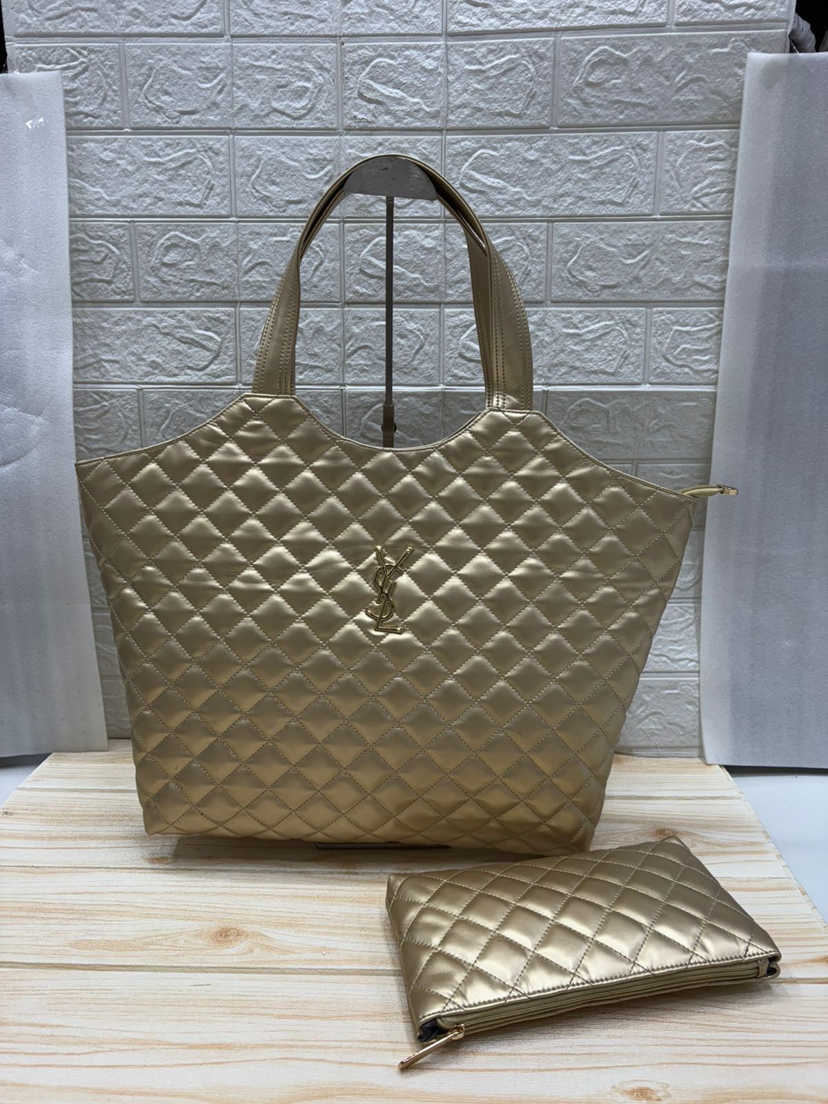 Brown YSL Big Size Tote Bag with Small Wallet quilted handbag with a matching pouch on a light wooden surface.