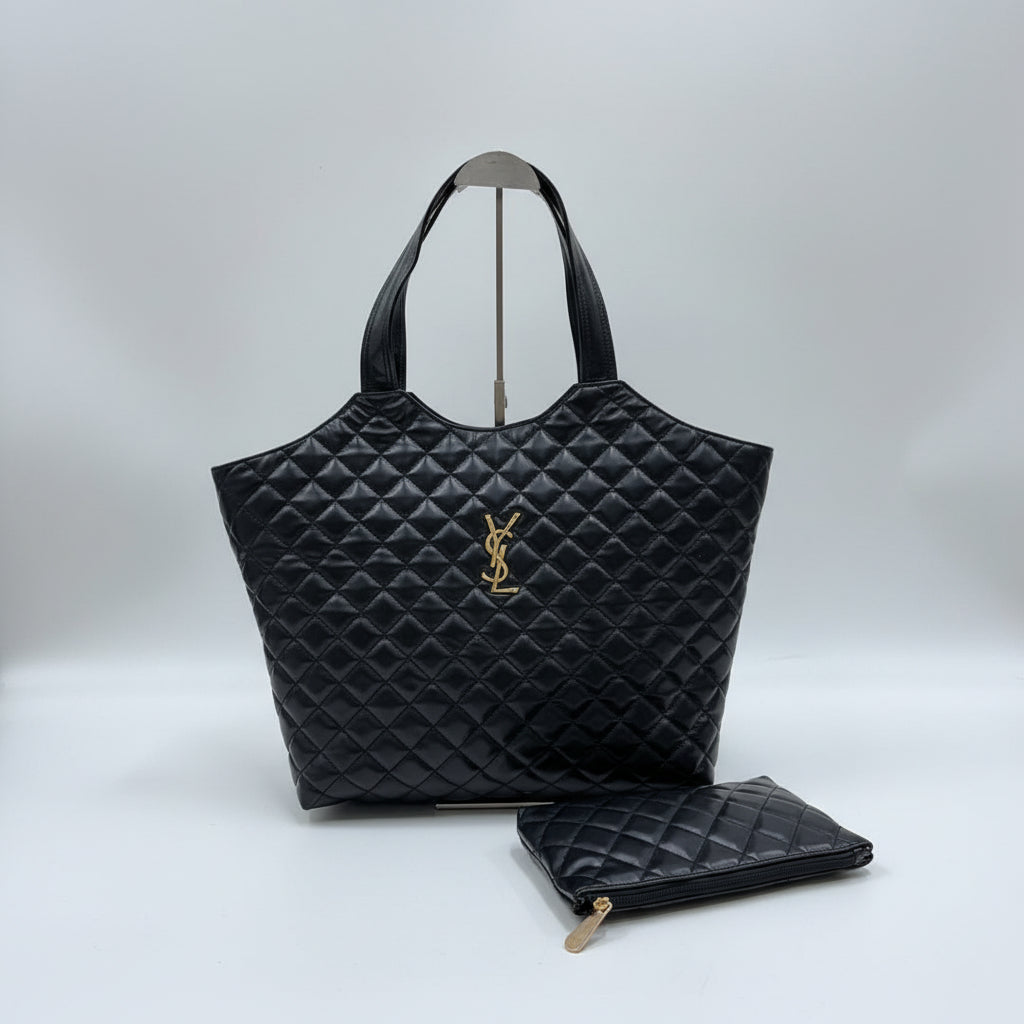 Black YSL Big Size Tote Bag with Small Wallet quilted handbag with a brand logo on a wooden surface against a textured wall.