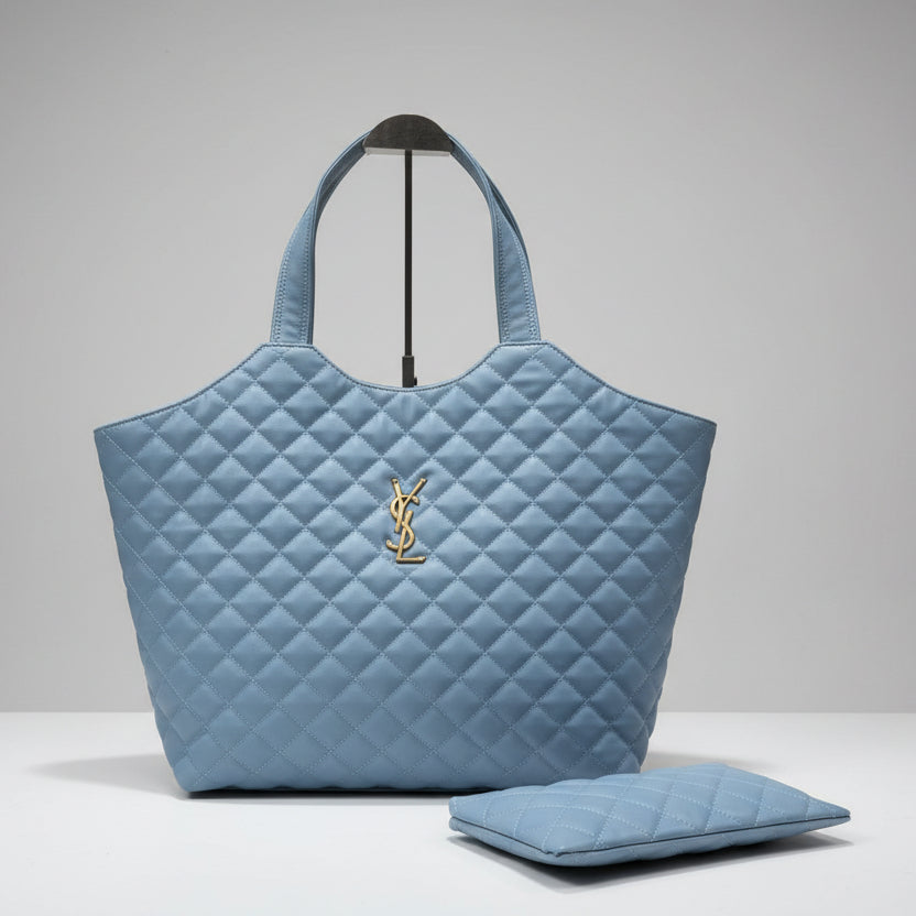 sky blue YSL Big Size Tote Bag with Small Wallet quilted handbag with a logo on a wooden surface against a textured wall.
