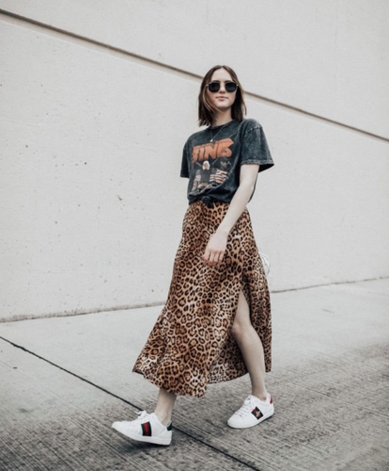Gucci Ace Embroidered ‘Bee’  Woman wearing a graphic t-shirt and leopard print skirt with white sneakers against a light-colored wall.