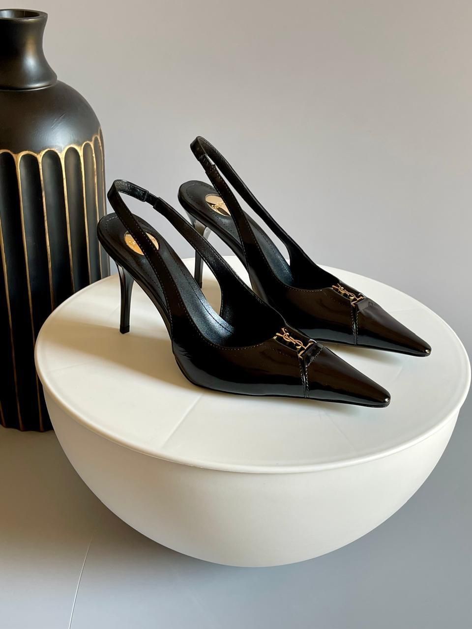 YSL Babylone Women’s Pumps Black high-heeled shoes on a white surface with a black vase in the background