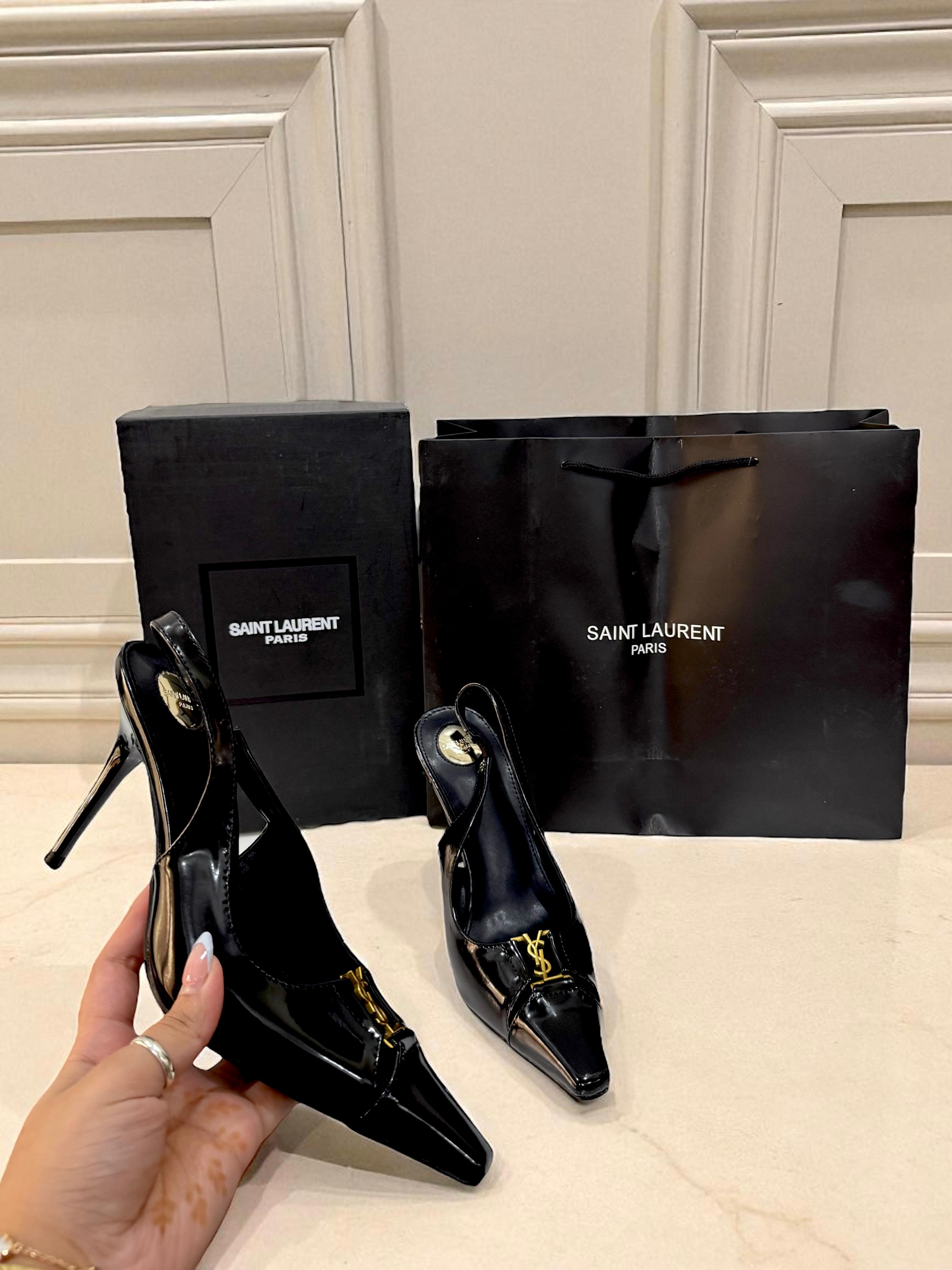 YSL Babylone Women’s Pumps Black high-heeled shoes with Saint Laurent packaging on a light-colored surface.