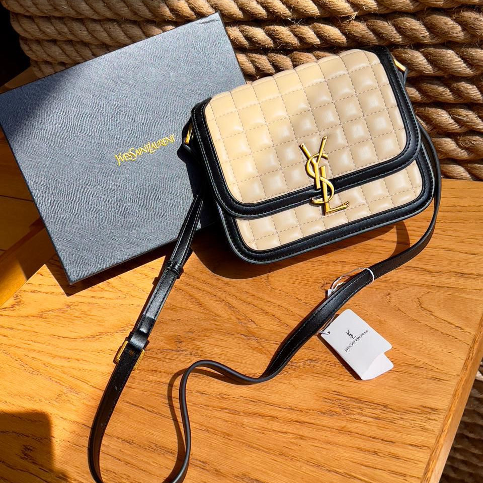 Beige Yves Saint Laurent YSL Premium Shoulder Bag quilted handbag with black strap and YSL logo on a wooden surface.